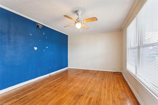 empty room with baseboards, ceiling fan, ornamental molding, a textured ceiling, and light wood-style floors