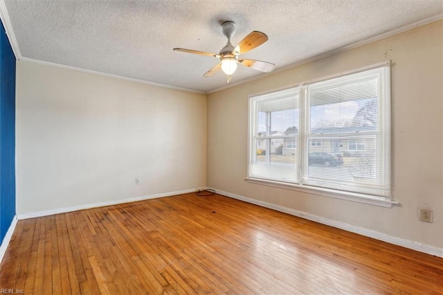 empty room featuring ornamental molding, a ceiling fan, a textured ceiling, baseboards, and hardwood / wood-style flooring