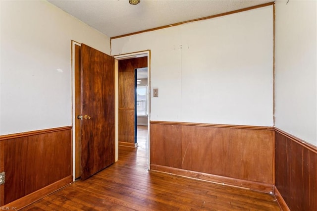 spare room featuring wood walls, wainscoting, and hardwood / wood-style flooring