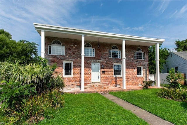 view of front of home with brick siding, fence, and a front lawn