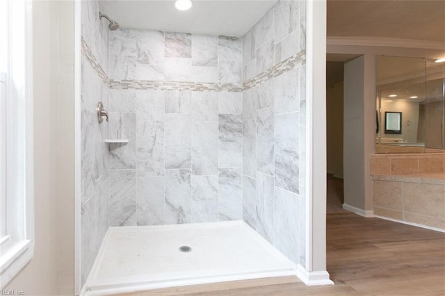 bathroom with tiled shower and wood finished floors