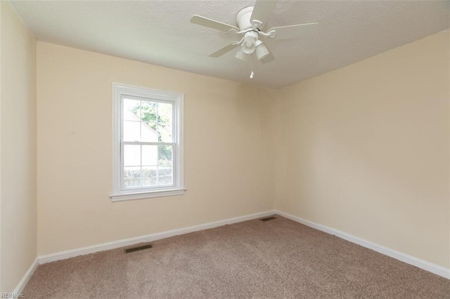 unfurnished room featuring visible vents, baseboards, a ceiling fan, carpet, and a textured ceiling