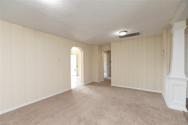 spare room featuring arched walkways, carpet floors, visible vents, and ornate columns