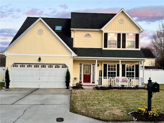 traditional-style home featuring fence, a porch, a front yard, a garage, and driveway