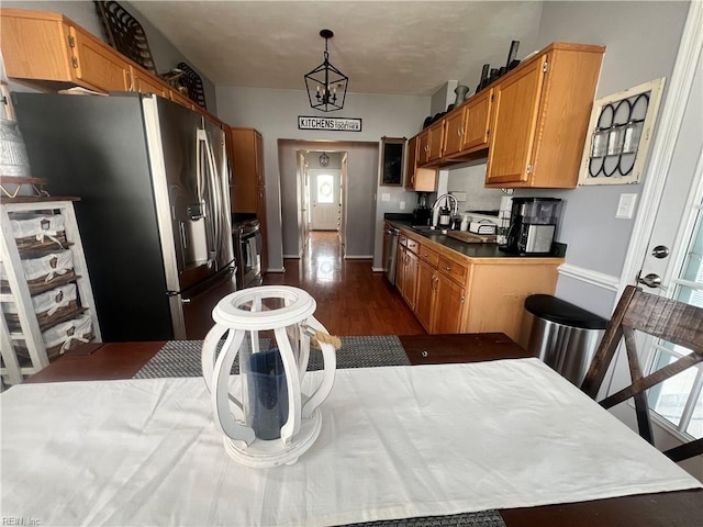 kitchen with baseboards, dark wood finished floors, appliances with stainless steel finishes, a notable chandelier, and a sink