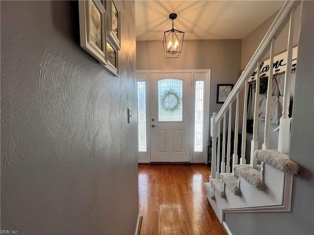 entrance foyer featuring an inviting chandelier, wood finished floors, and stairs