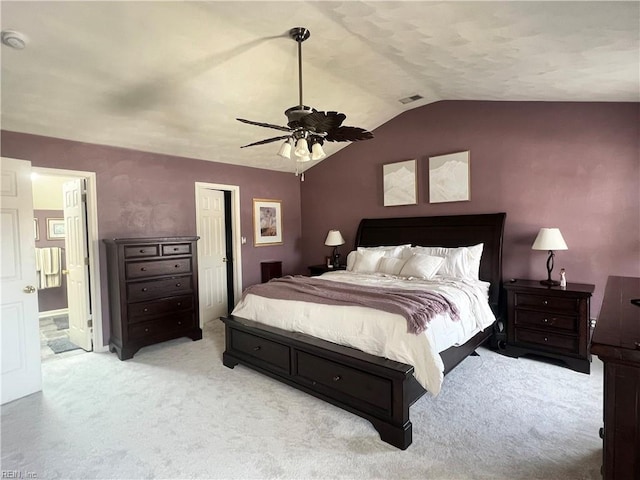 bedroom featuring visible vents, lofted ceiling, ceiling fan, light carpet, and connected bathroom