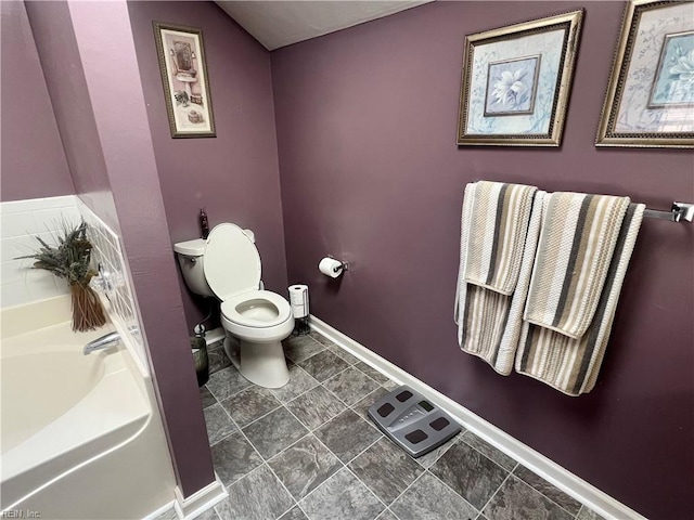 bathroom featuring a garden tub, toilet, and baseboards