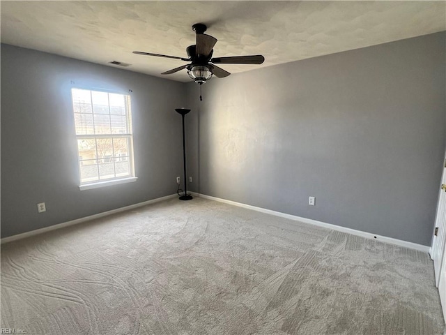 empty room with carpet flooring, baseboards, visible vents, and ceiling fan