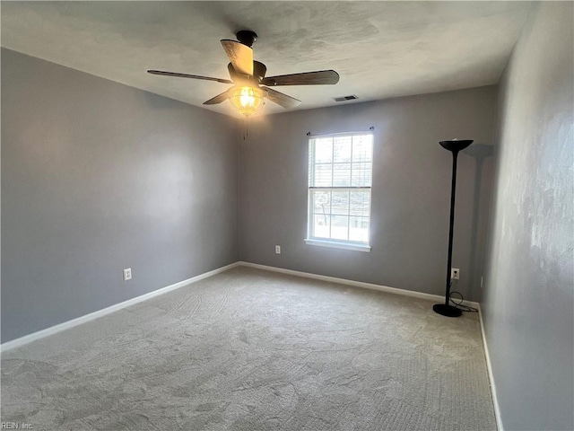 spare room with visible vents, carpet floors, baseboards, and a ceiling fan