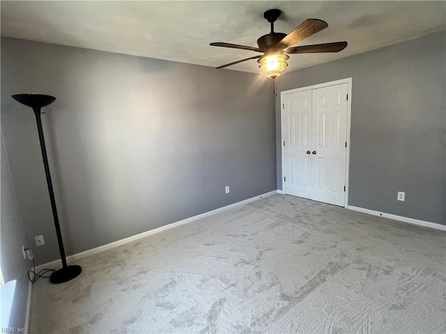 unfurnished bedroom featuring carpet, baseboards, a closet, and ceiling fan