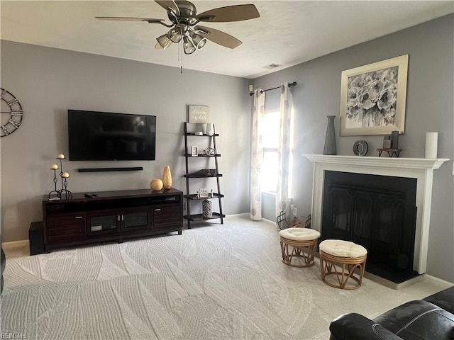 carpeted living area featuring visible vents, a fireplace, a ceiling fan, and baseboards