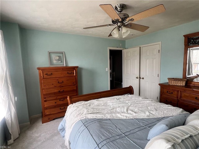 bedroom with baseboards, light colored carpet, a closet, and ceiling fan