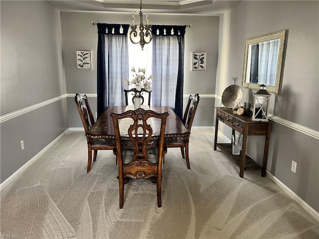 dining space featuring a notable chandelier, carpet flooring, baseboards, and a tray ceiling