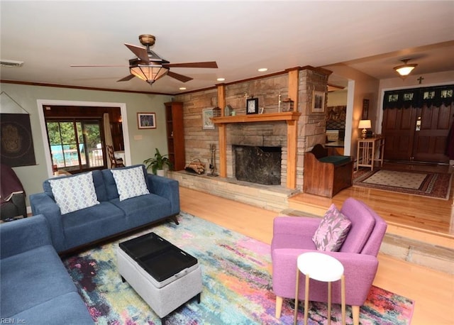 living room with a fireplace, wood finished floors, visible vents, and crown molding