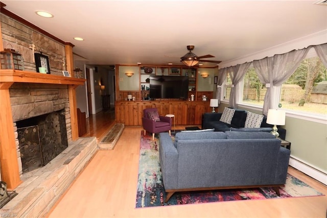 living room featuring recessed lighting, a baseboard heating unit, a fireplace, wood finished floors, and a ceiling fan