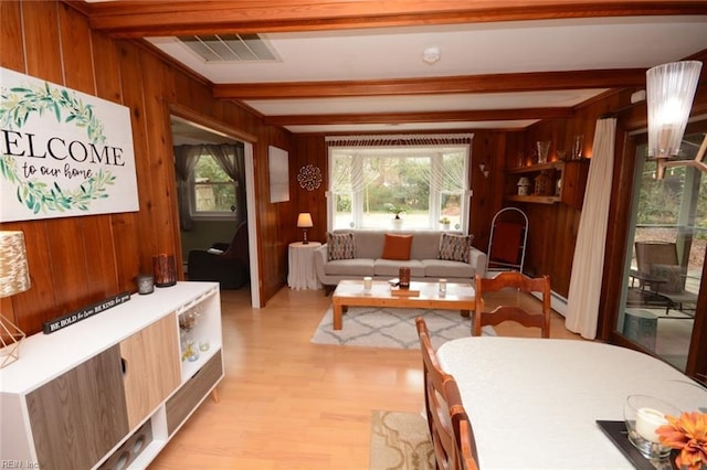 interior space featuring a baseboard heating unit, wood walls, visible vents, beam ceiling, and light wood finished floors