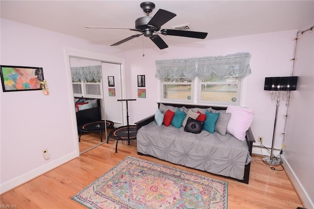 bedroom with a baseboard heating unit, ceiling fan, wood finished floors, and baseboards