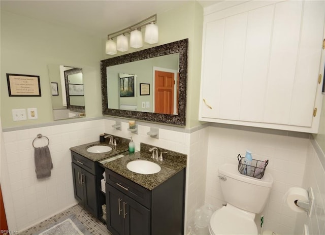 bathroom featuring a wainscoted wall, tile walls, toilet, and vanity