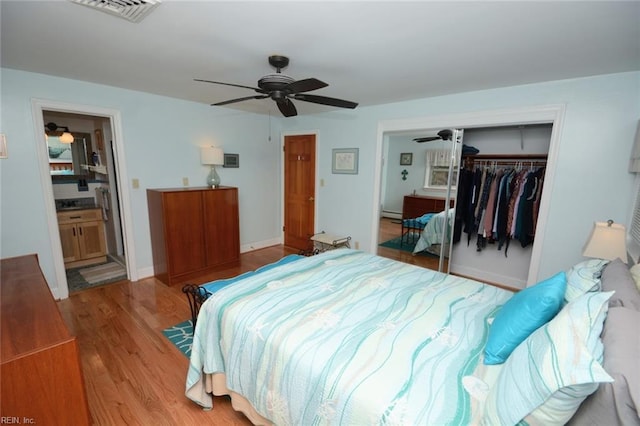 bedroom with a closet, visible vents, a ceiling fan, wood finished floors, and baseboards