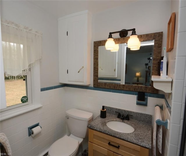 bathroom with toilet, wainscoting, tile walls, and vanity