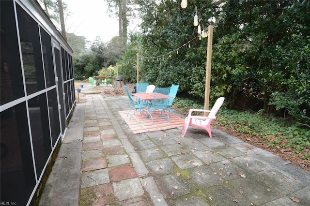 view of patio with outdoor dining space and a sunroom