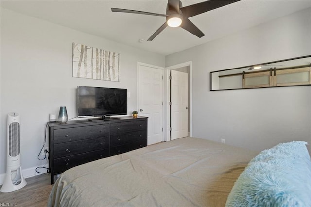 bedroom featuring ceiling fan, baseboards, and wood finished floors