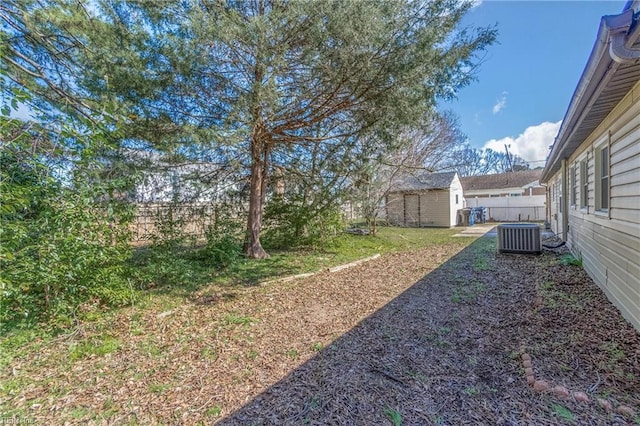 view of yard with an outbuilding, central AC, and fence