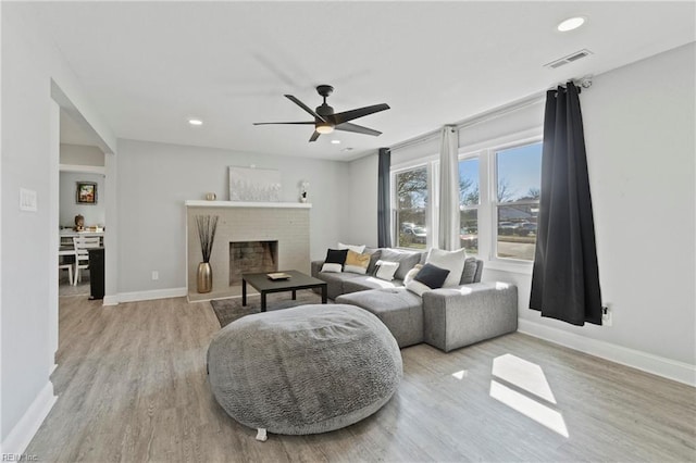 living room with visible vents, baseboards, wood finished floors, a fireplace, and recessed lighting