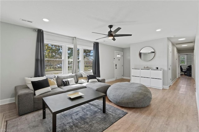 living room featuring baseboards, recessed lighting, and light wood-style floors