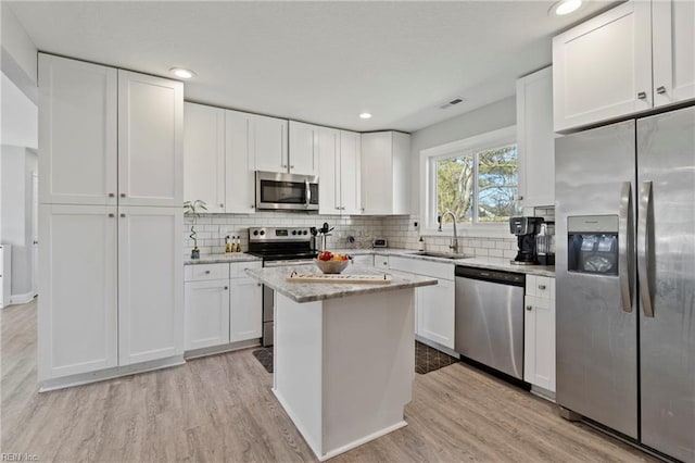 kitchen featuring stainless steel appliances, light wood-type flooring, white cabinets, and a sink