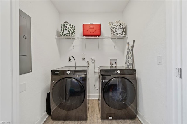 clothes washing area featuring laundry area, baseboards, washer and clothes dryer, and wood finished floors