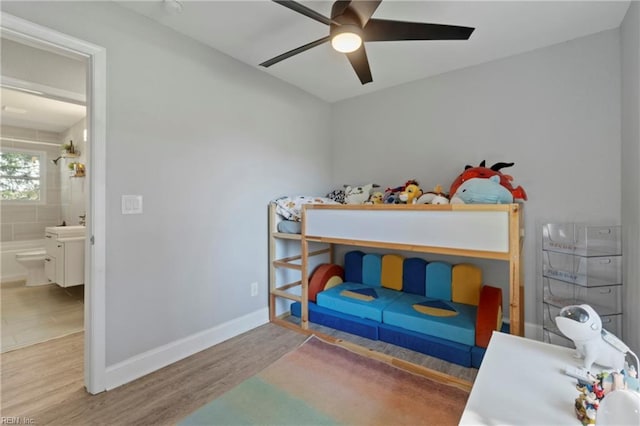 bedroom featuring a ceiling fan, connected bathroom, baseboards, and wood finished floors