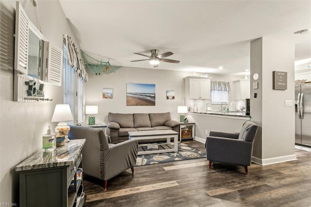 living area featuring baseboards, a ceiling fan, and dark wood-style flooring