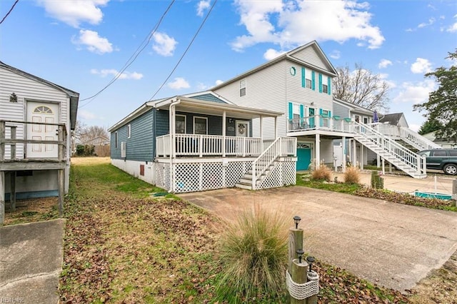 back of property with stairs, driveway, and a porch