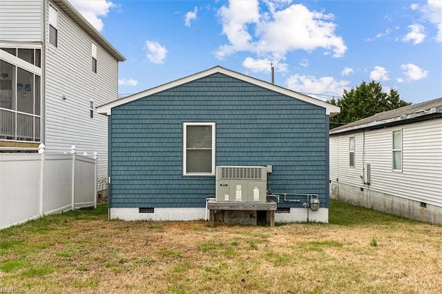 rear view of property featuring a yard, crawl space, and fence