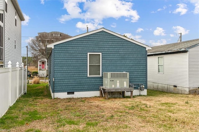 rear view of house with crawl space, cooling unit, fence, and a lawn