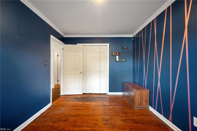 unfurnished bedroom featuring baseboards, a closet, ornamental molding, and wood finished floors