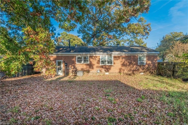 rear view of house featuring crawl space, fence, and brick siding