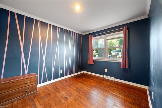 empty room featuring ornamental molding, visible vents, hardwood / wood-style floors, and baseboards