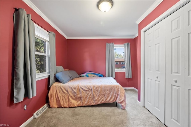 carpeted bedroom featuring ornamental molding, a closet, visible vents, and multiple windows