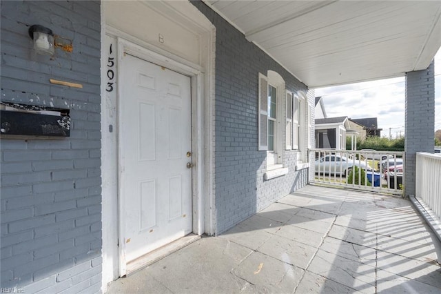 property entrance featuring a porch and brick siding