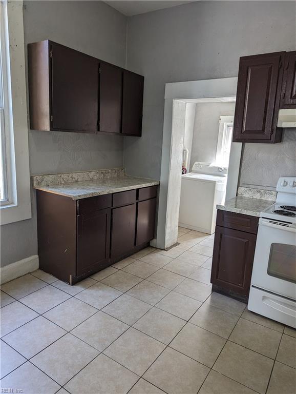 kitchen featuring dark brown cabinetry, washer / dryer, white range with electric stovetop, light countertops, and under cabinet range hood