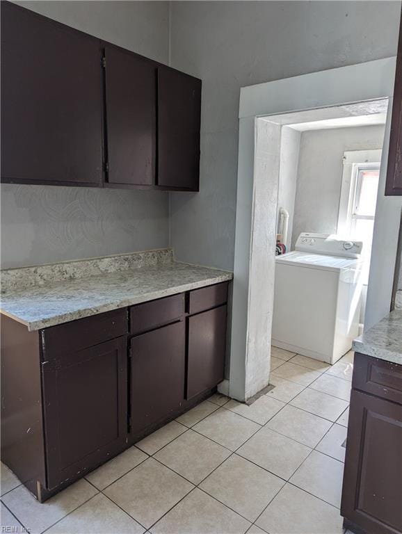 kitchen featuring washer / dryer, light tile patterned floors, light countertops, and dark brown cabinets