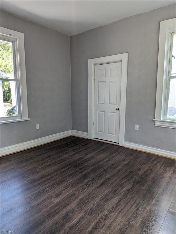 empty room featuring dark wood-type flooring and baseboards