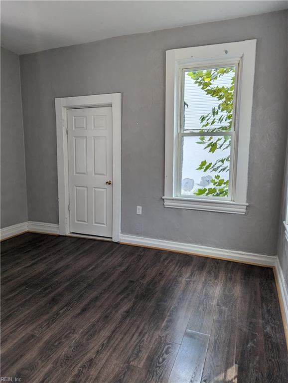 spare room with dark wood-style floors and baseboards