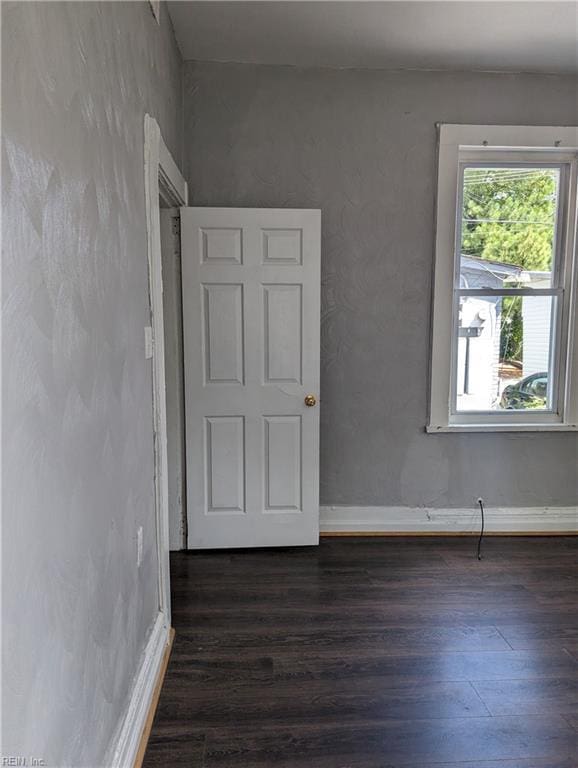 unfurnished room with baseboards and dark wood-type flooring