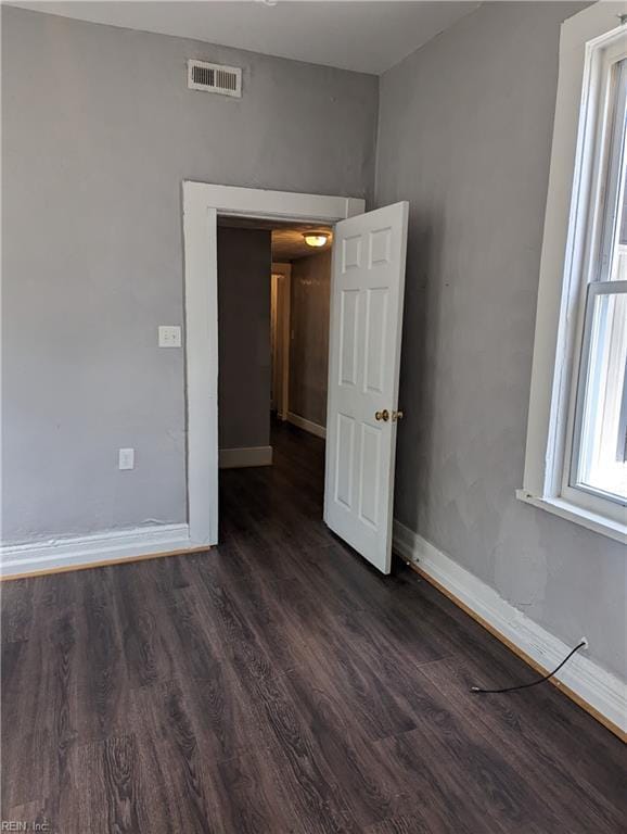 unfurnished room featuring baseboards, visible vents, and dark wood-type flooring