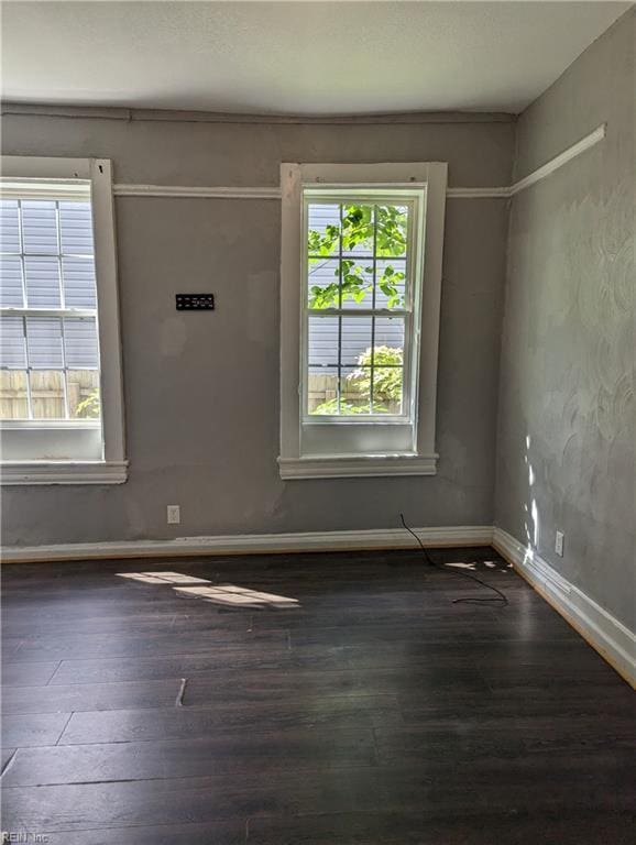 spare room featuring dark wood finished floors and baseboards