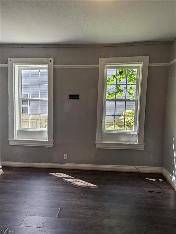 empty room featuring dark wood-style flooring and baseboards